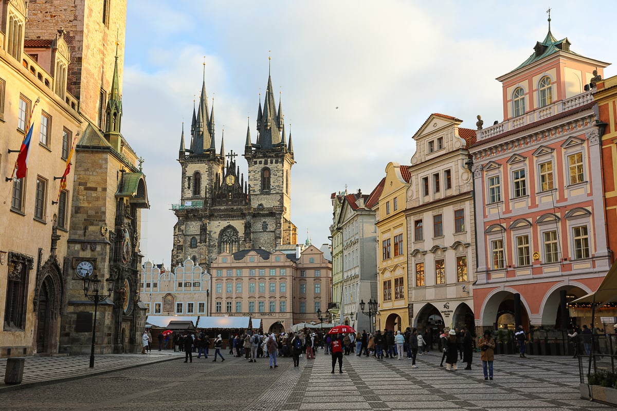 Old Town Square in Prague with cobblestone streets, pastel Baroque buildings, and the twin spires of the Church of Our Lady before Týn