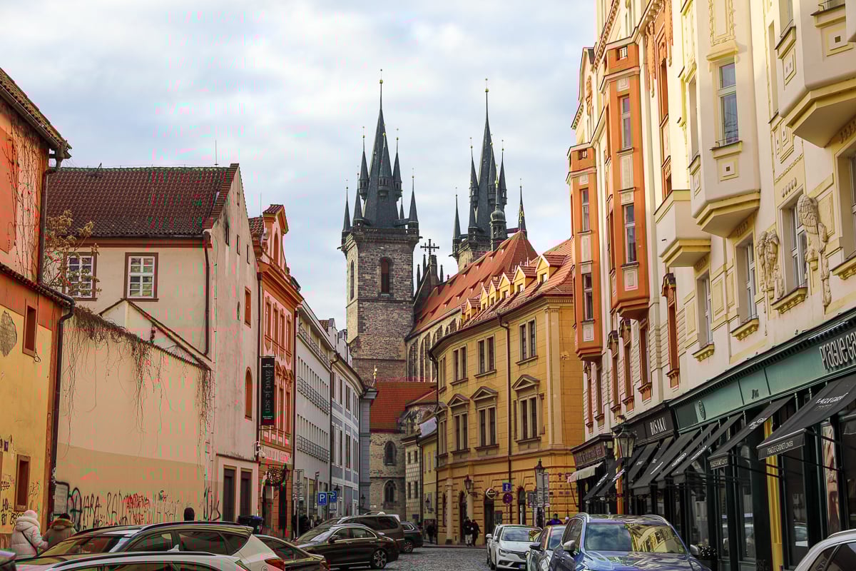 Colorful street in Prague’s Old Town with Gothic church towers rising between historic buildings, showcasing classic architecture in one of the most popular Prague neighborhoods.