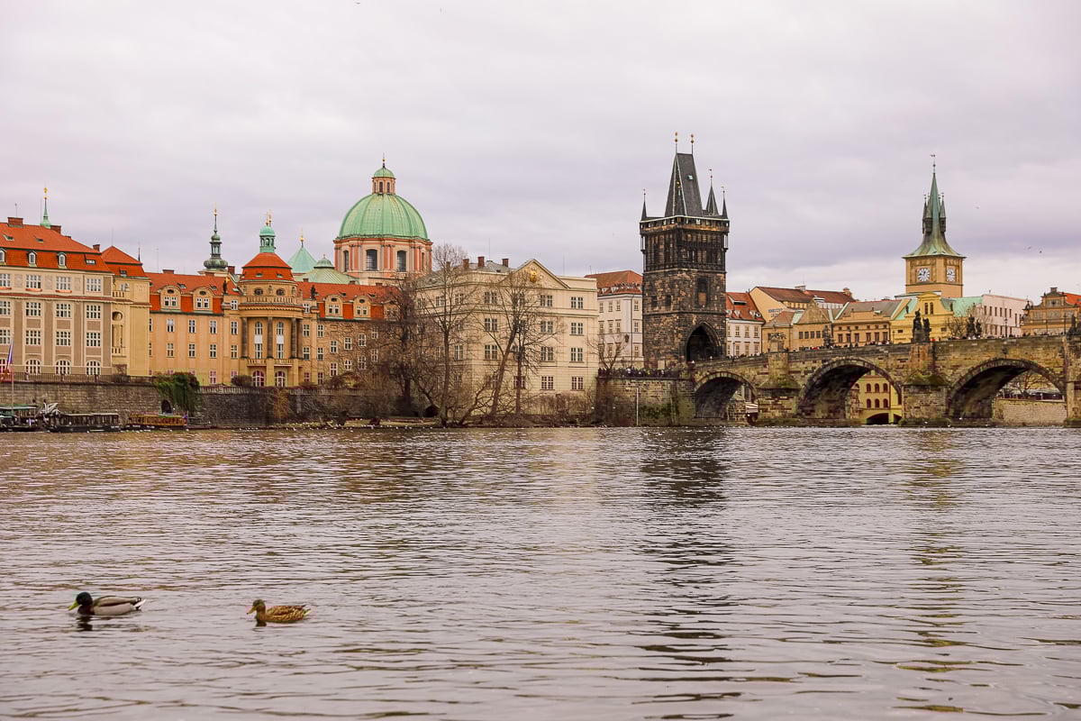 View of Charles Bridge and Prague skyline from the Vltava River on an overcast day