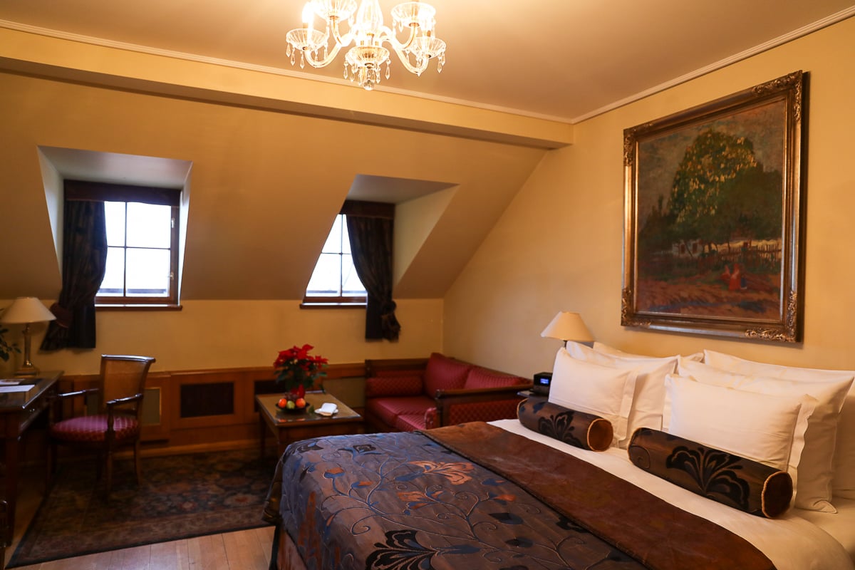 Classic boutique hotel room at Golden Well Hotel Prague, featuring warm wood accents, chandeliers, and vintage décor.