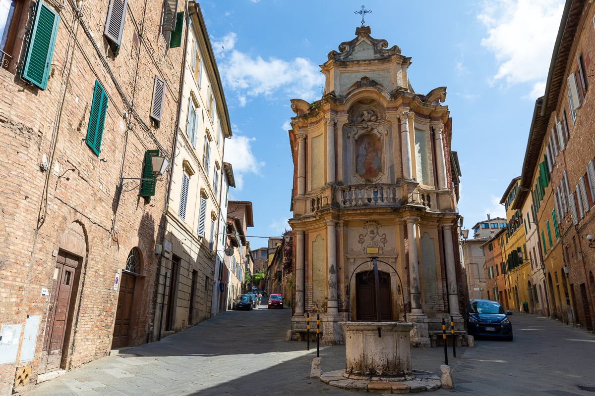Historic street and fountain in Siena’s old town, surrounded by medieval brick buildings