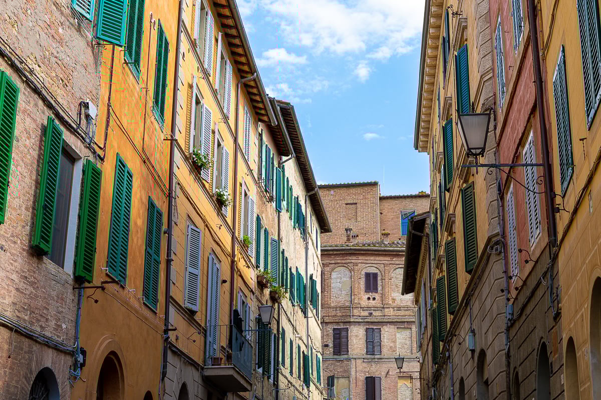 Colorful medieval street in Siena, Italy with shuttered windows and warm brick buildings