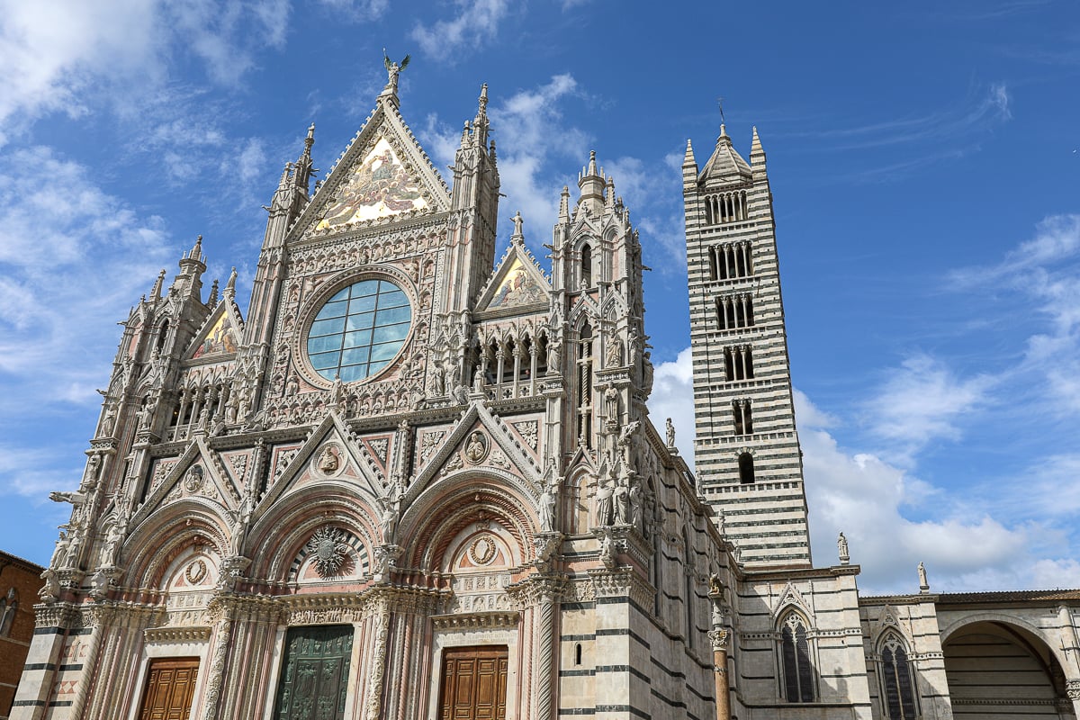 Exterior view of the Duomo di Siena and bell tower against a blue sky