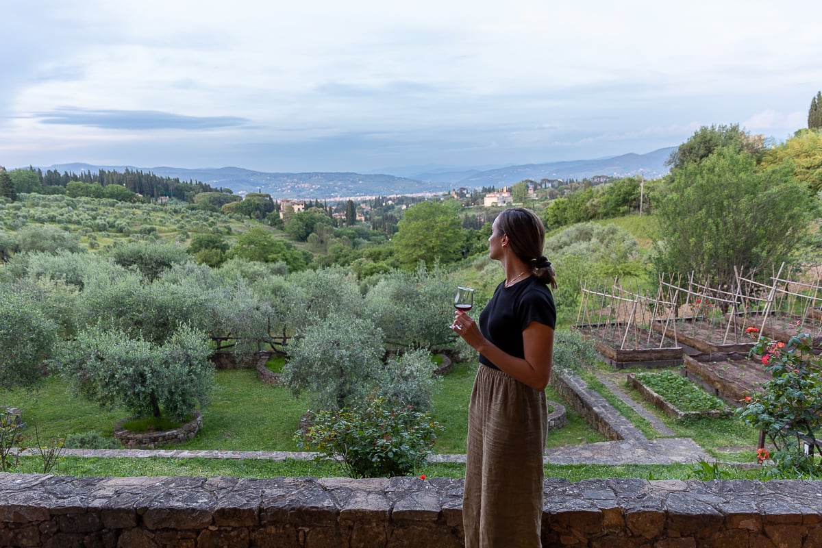 Maddy enjoying a glass of Tuscan red wine while overlooking olive groves and rolling hills in the Siena countryside