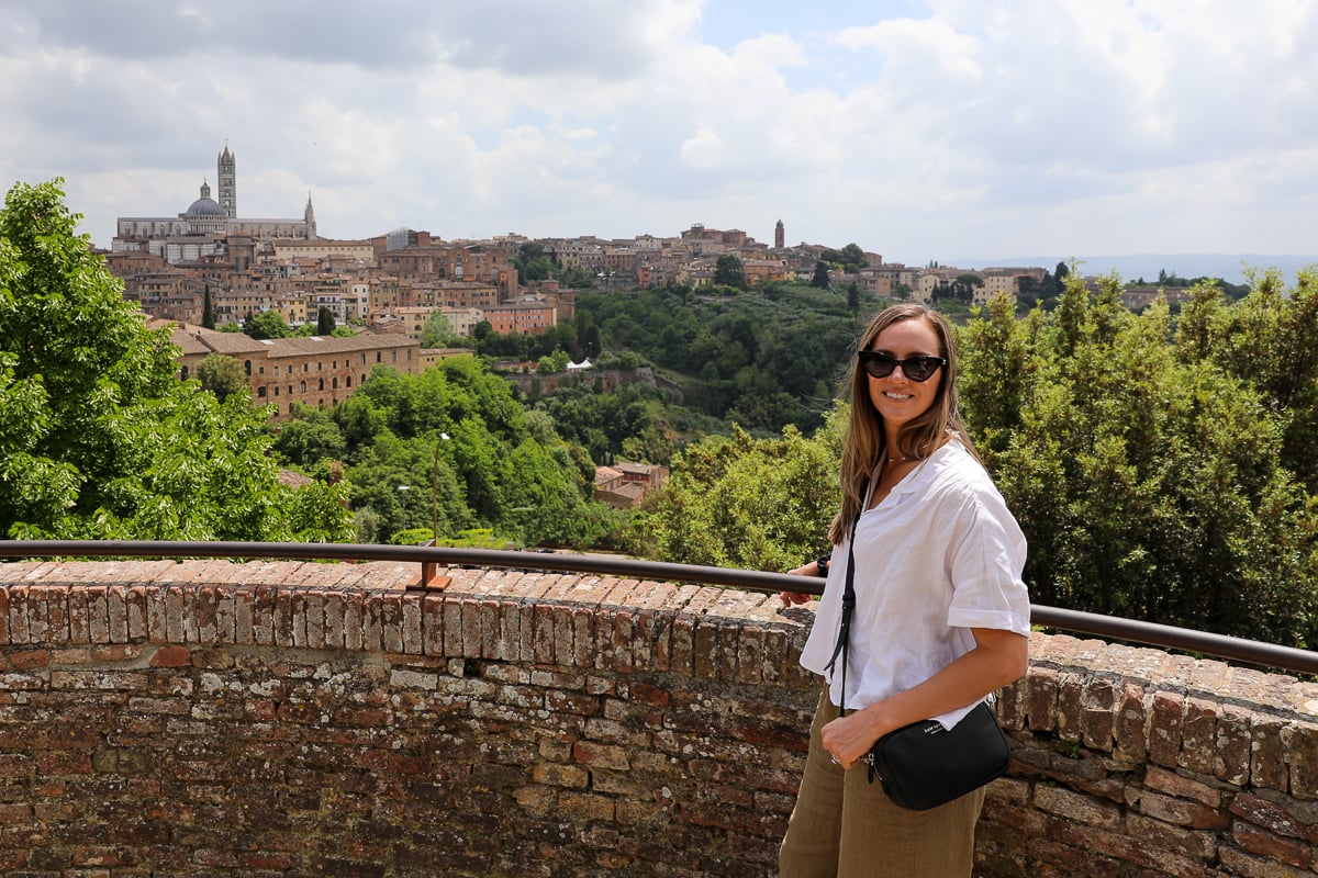 Woman standing at a scenic viewpoint overlooking Siena’s historic center and countryside