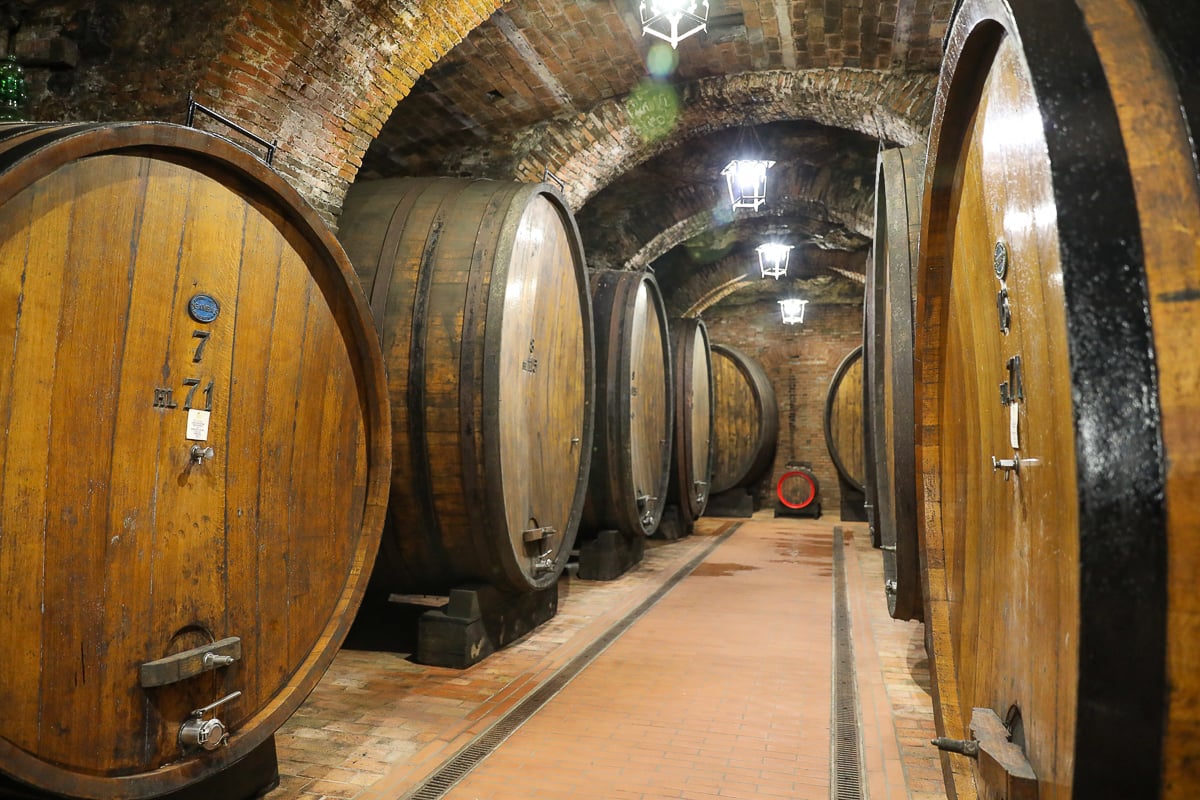 Large wooden wine barrels lining an underground cellar in Montepulciano