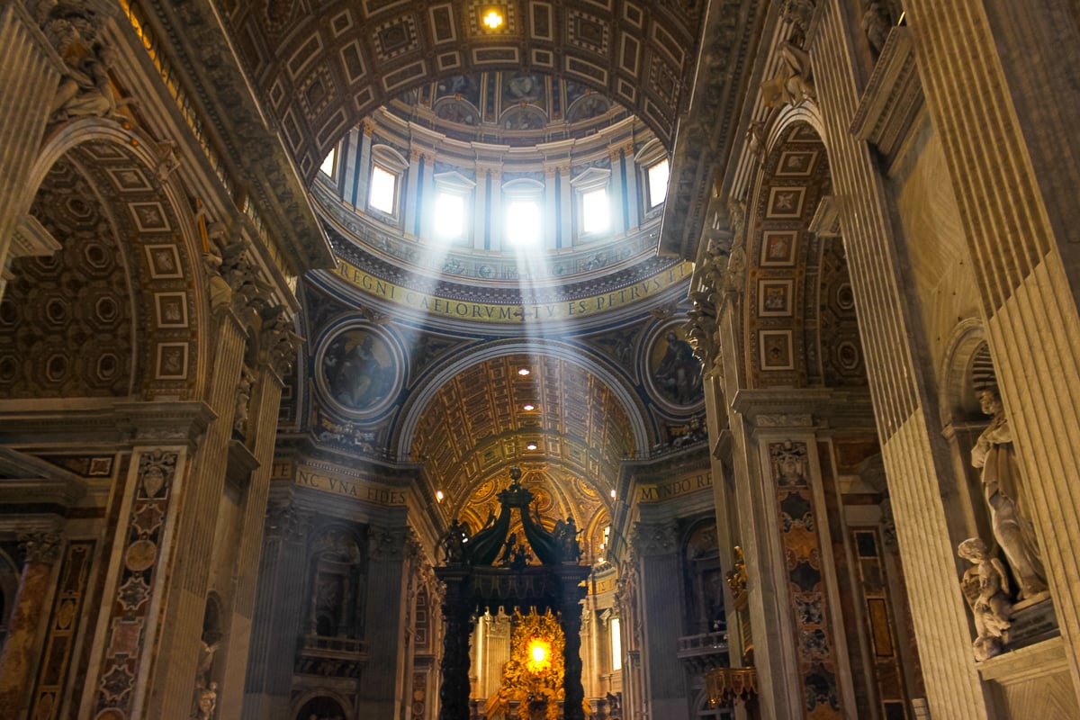 Interior of St. Peter’s Basilica showing massive columns, the central altar, and light streaming down from the dome