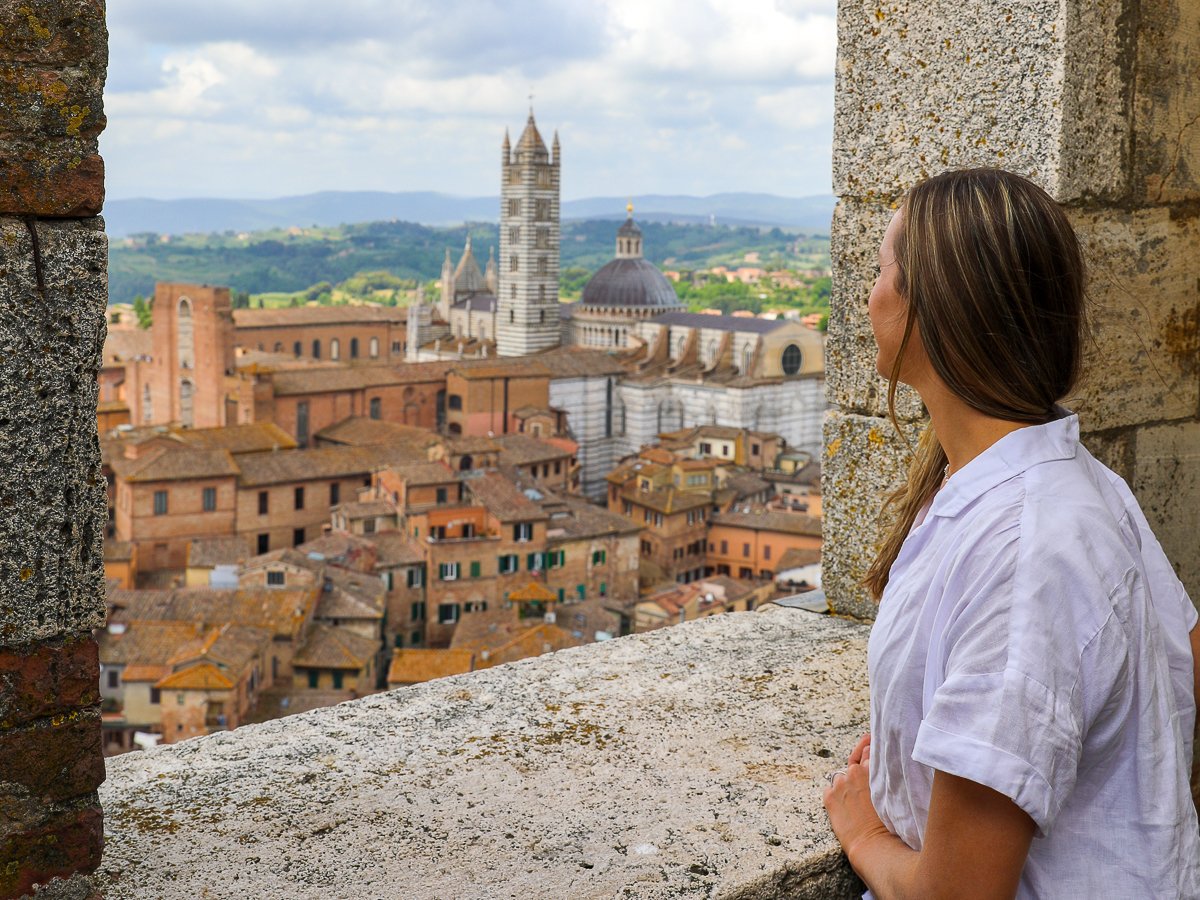 Woman overlooking Siena from a the Torre del Mangia with the Duomo di Siena in view