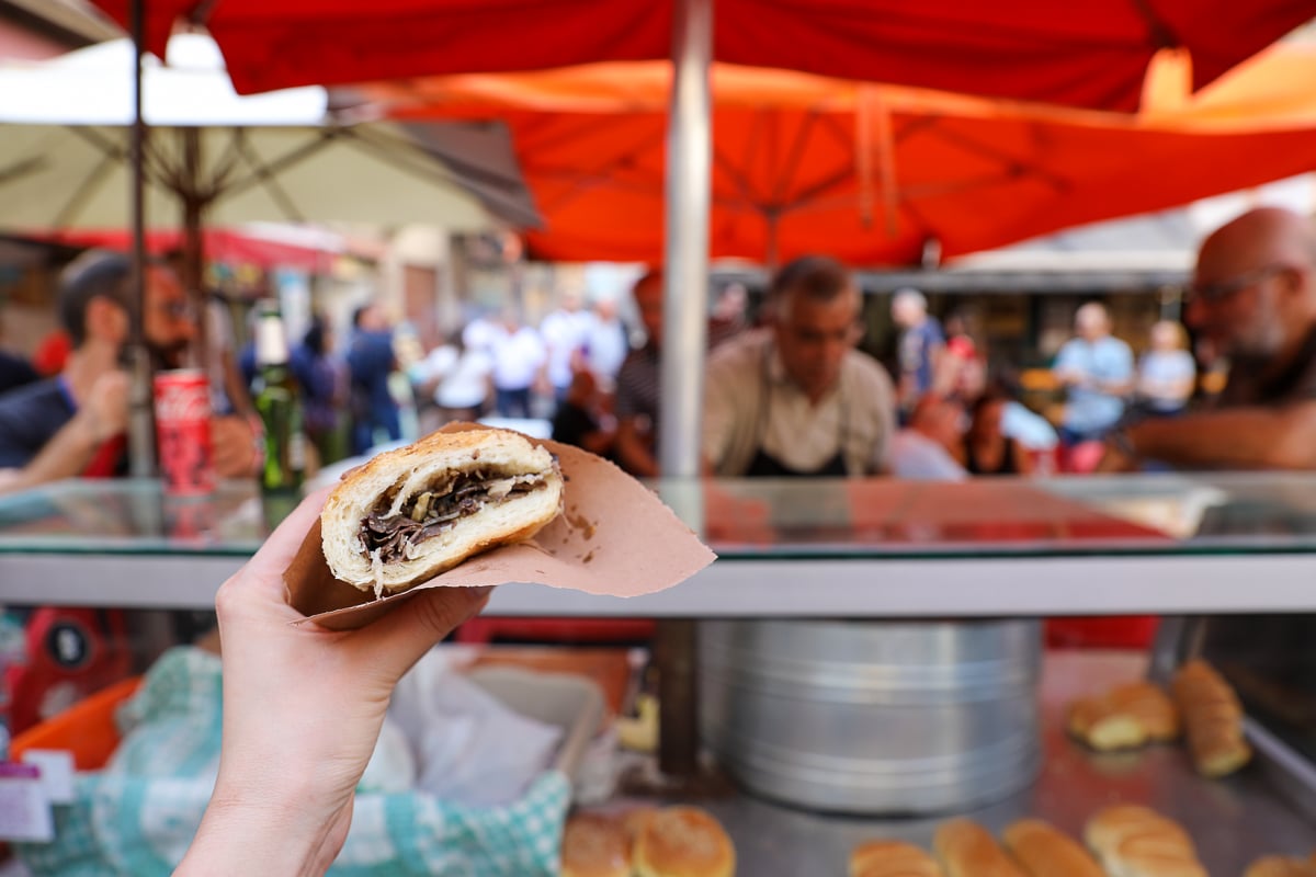 Pani ca meusa sandwich held up at La Vucciria Market, a must-try Palermo street food in Sicily