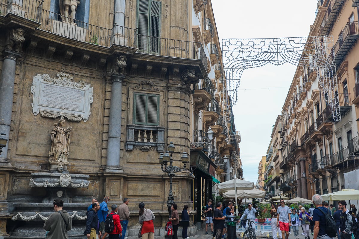 Quattro Canti intersection in Palermo with baroque façades, street crowd, and decorative lights overhead