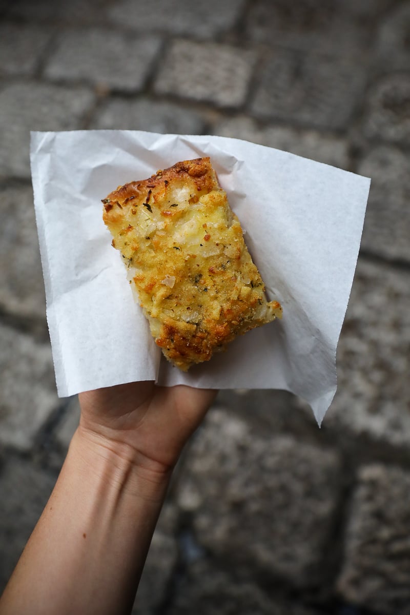 Slice of sfincione Sicilian pizza held in hand on a Palermo street in Sicily