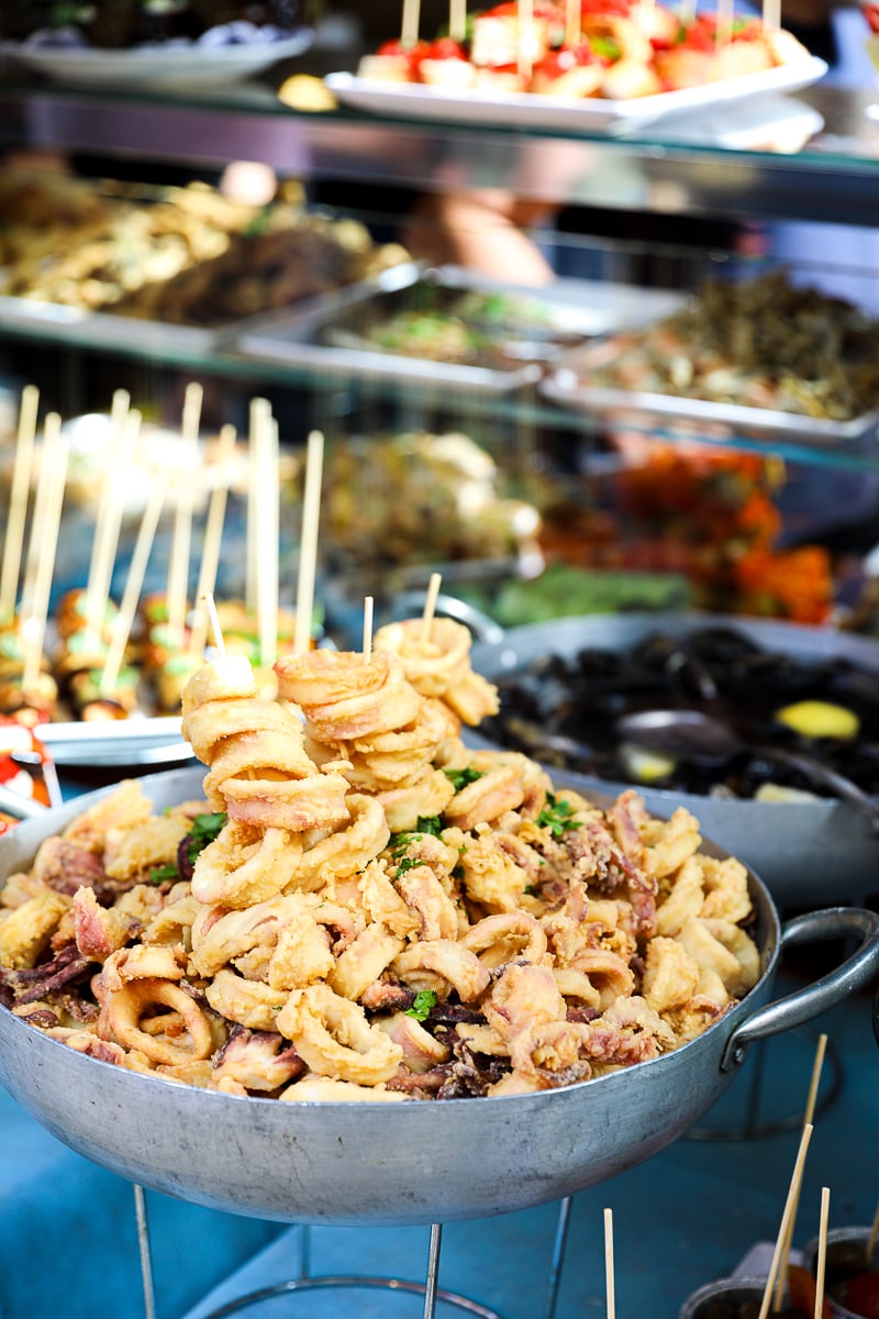 Palermo street food stall with fried calamari and seafood bites on skewers at a market in Sicily