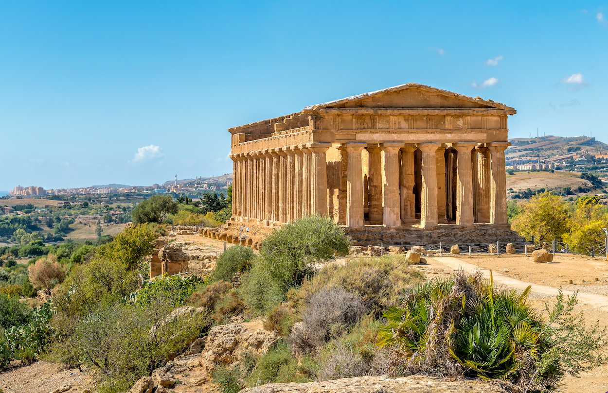 Ancient Greek temple ruins at the Valley of the Temples in Agrigento, Sicily, under a bright blue sky
