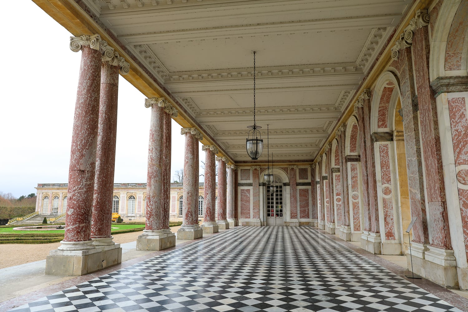 Grand Trianon marble colonnade on a day trip to Versailles from Paris, with pink columns and a black-and-white checkered floor