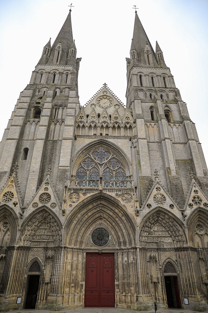Gothic façade of Bayeux Cathedral with twin spires and red wooden doors, Bayeux, France
