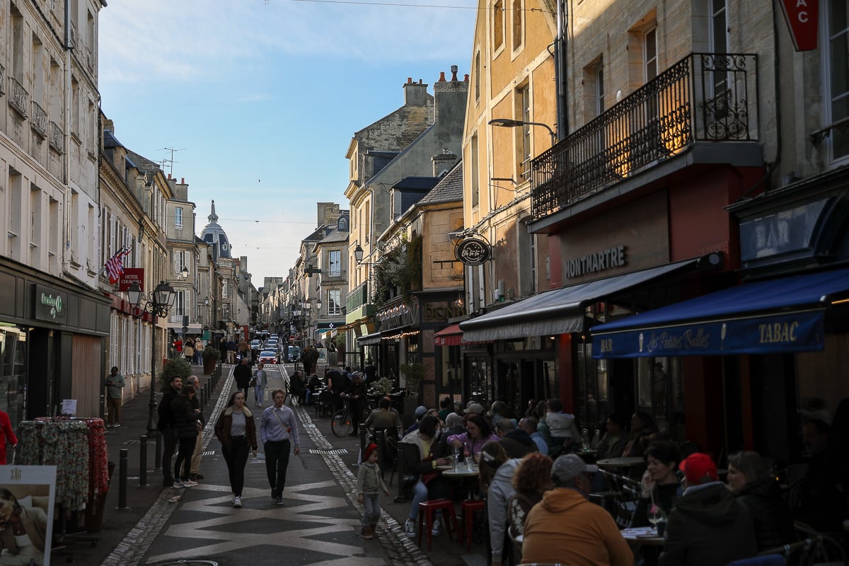 Busy pedestrian street Rue Saint-Jean lined with restaurants and shops in the historic center of Bayeux, France