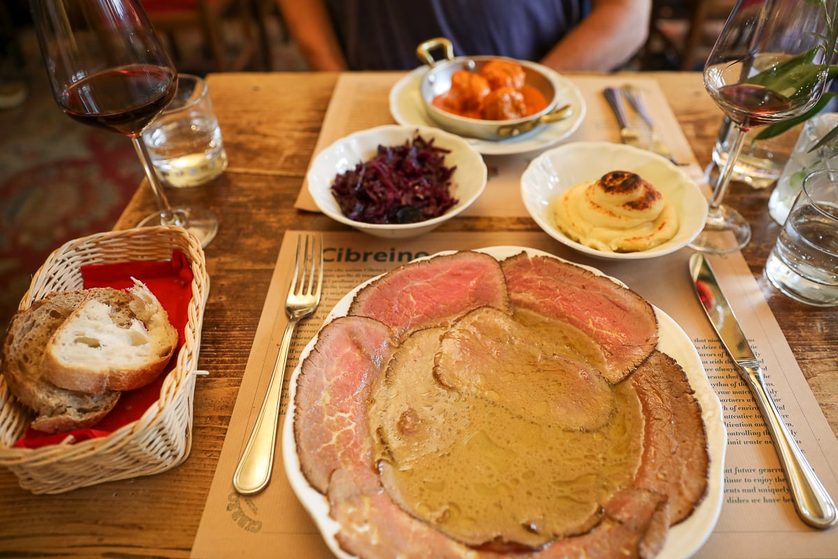 Table spread at Cibrèo Trattoria with thinly sliced roast beef in white wine broth, meatballs, mashed potatoes, and purple cabbage.