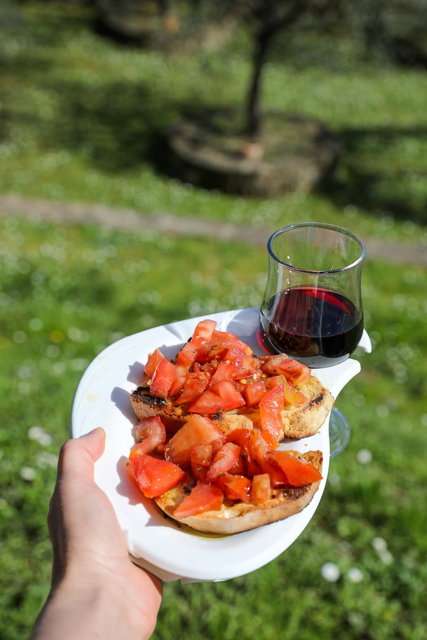 Classic Tuscan bruschetta topped with fresh tomatoes, served with a glass of red wine during a Tuscan cooking class near Florence.