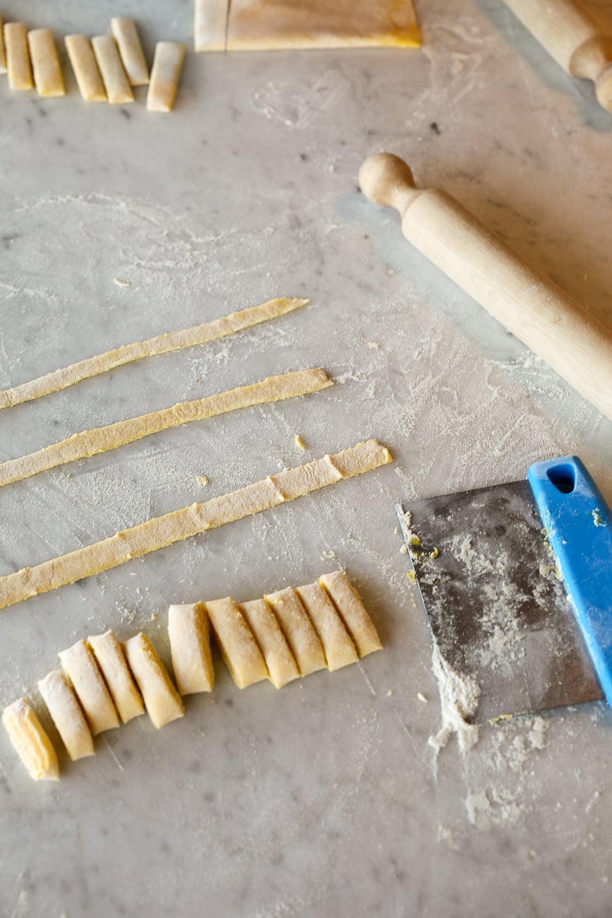 Hand-cut fresh pappardelle pasta noodles laid out on a marble countertop during a Tuscan cooking class.