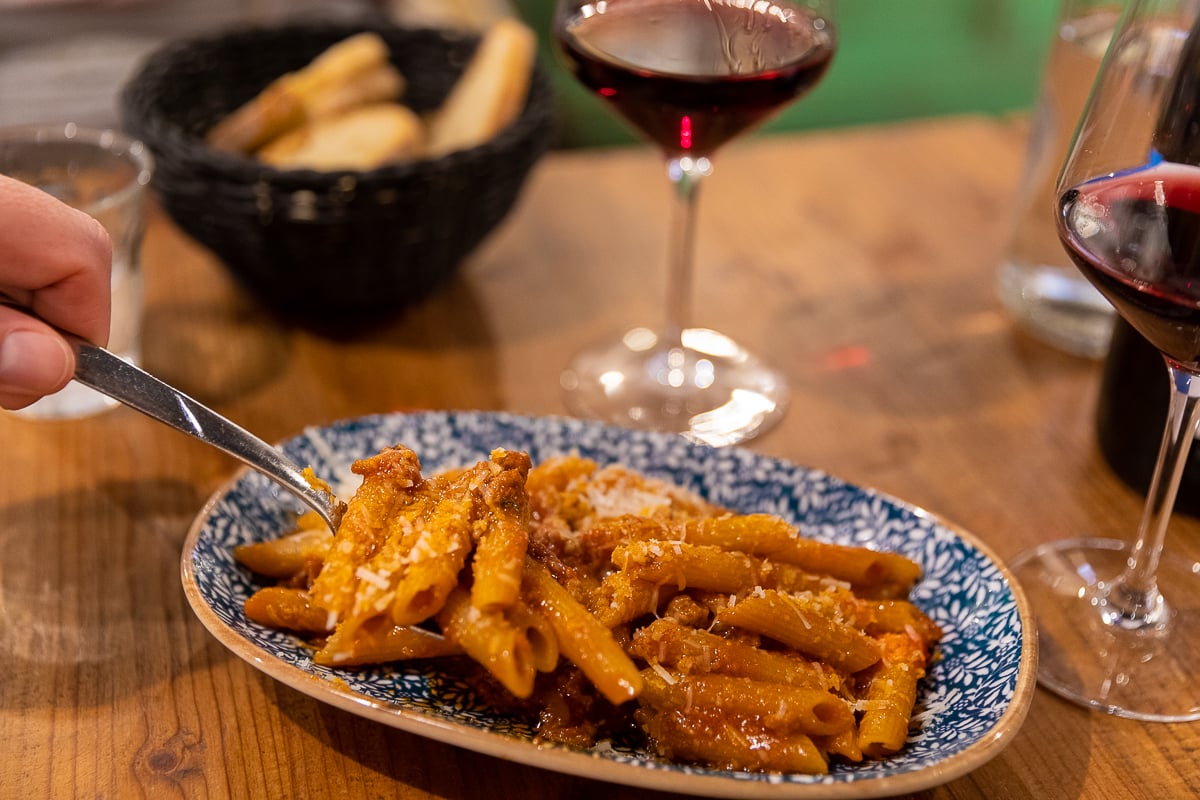 Fork digging into penne strascicate, Tuscan-style penne pasta with ragù, at Ristorante del Fagioli in Florence.
