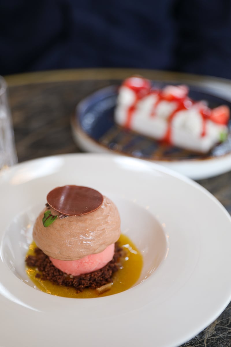 Chocolate dessert with orange sauce at Bonbonne restaurant in Bayeux, with a strawberry mousse in the background