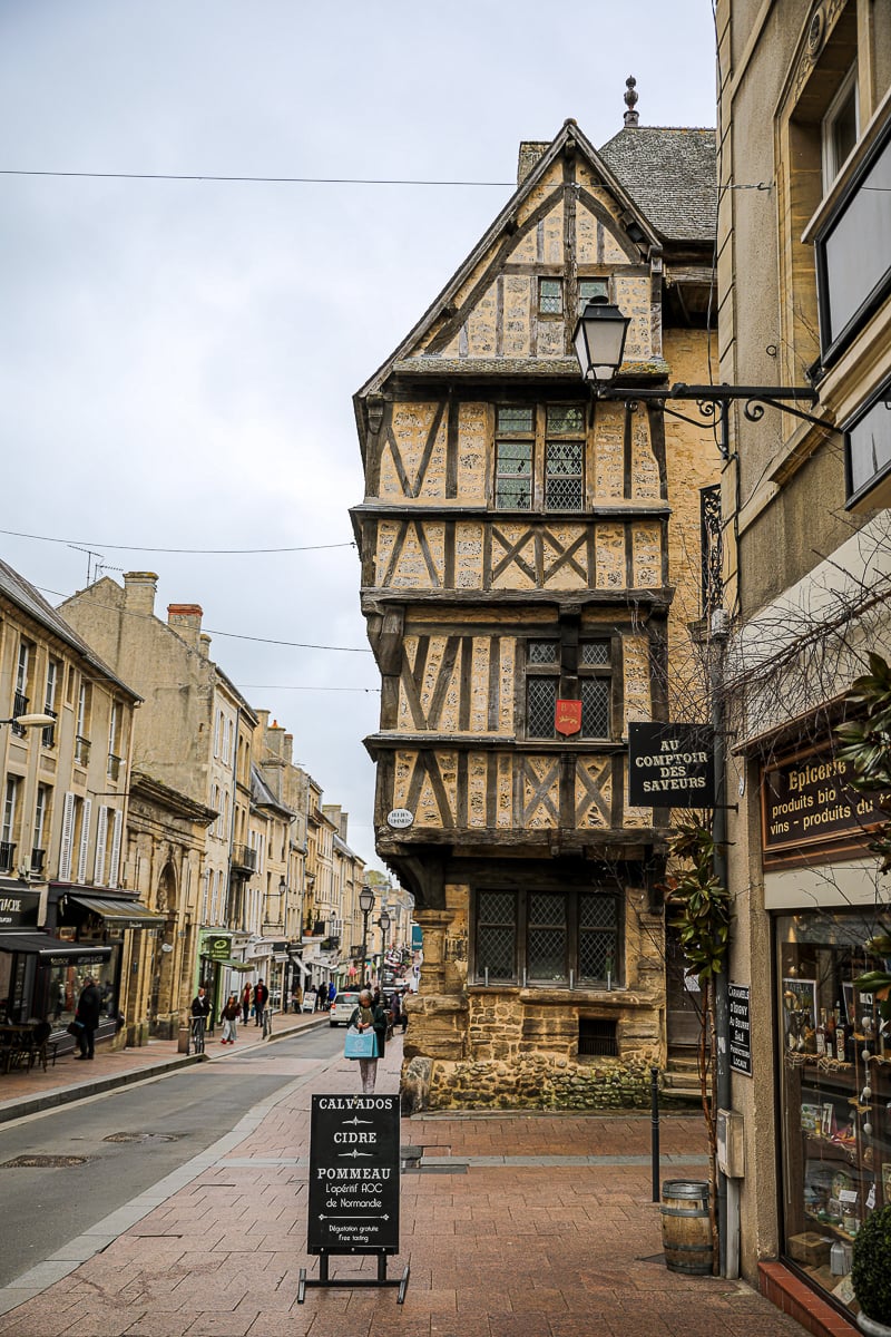 Medieval half-timbered building housing Au Comptoir des Saveurs wine shop with a Calvados and Cider tasting sign in Normandy
