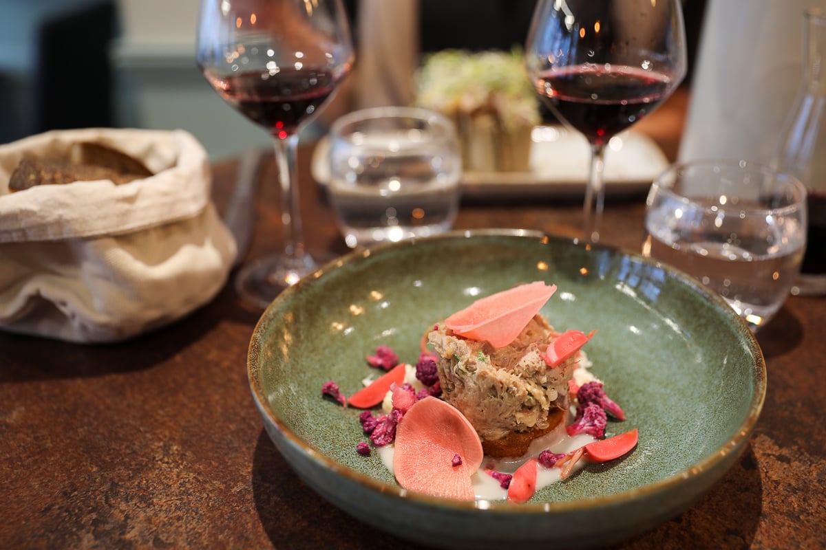 Beautifully plated fish dish with pink radish in a green ceramic bowl at L'Alcôve