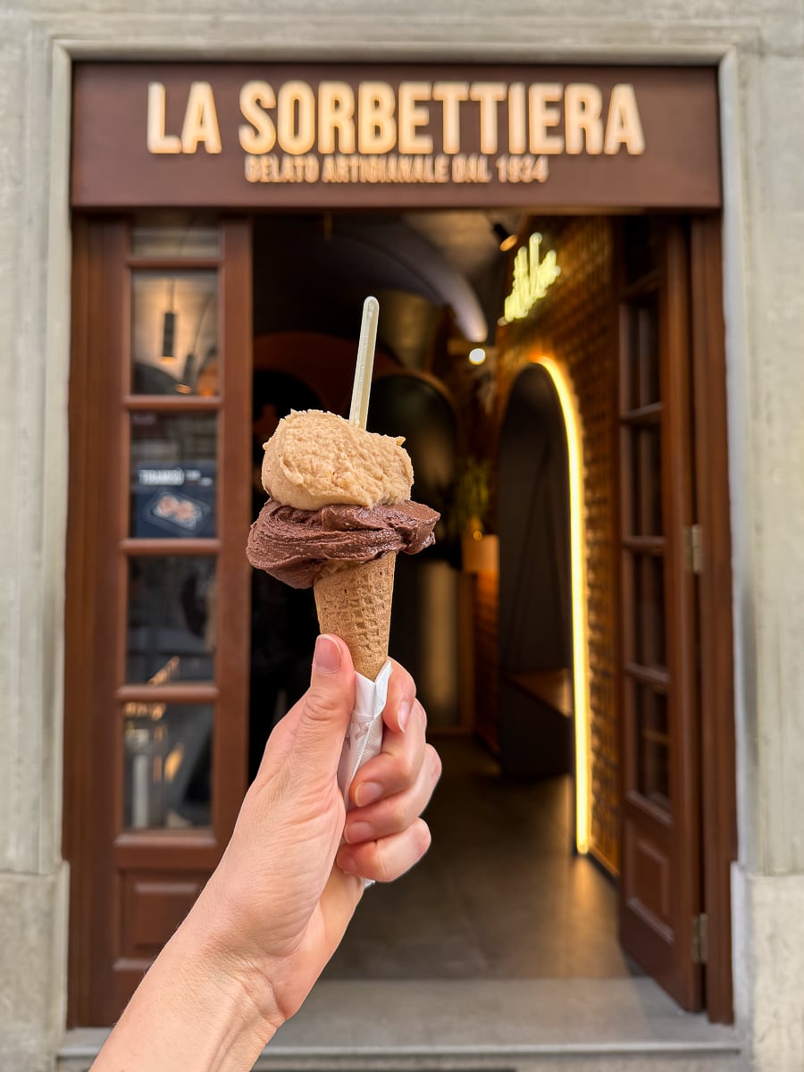 Hand holding a gelato cone with hazelnut and dark chocolate flavors outside La Sorbettiera in Florence.