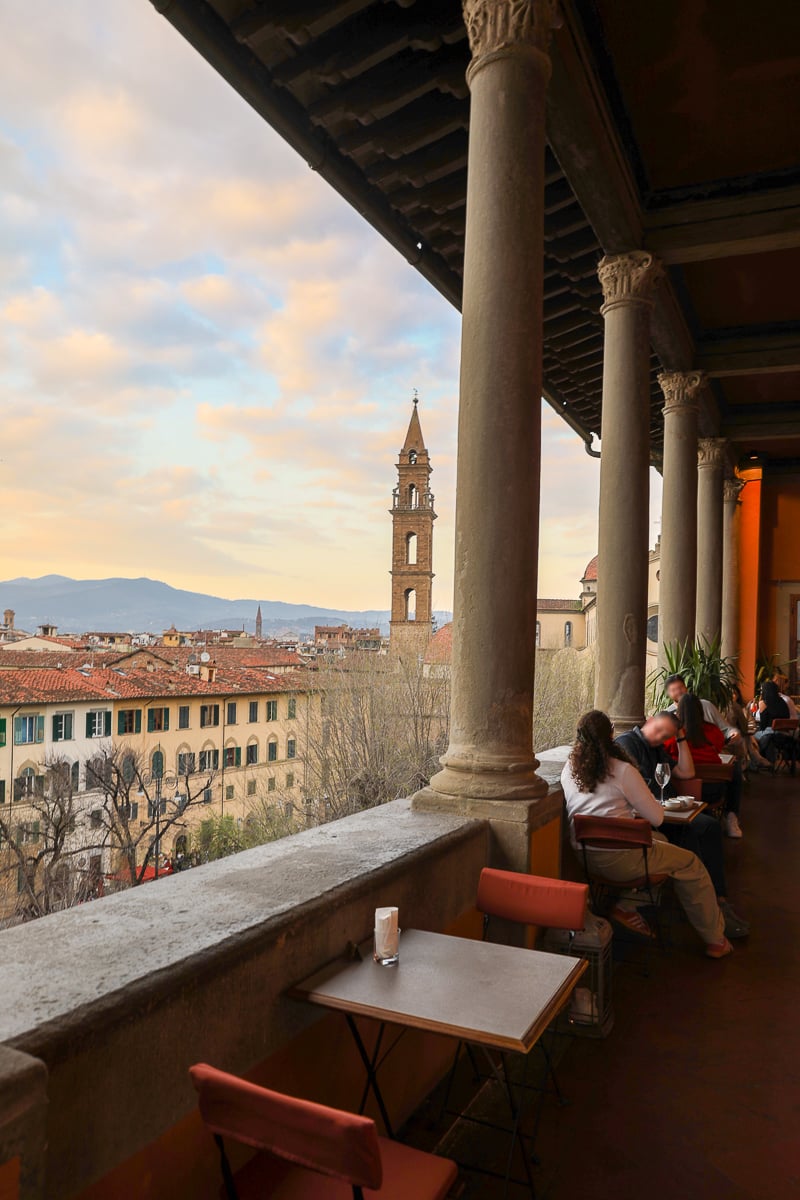 View of Florence rooftops and a historic bell tower from the covered terrace at Loggia Roof Bar.