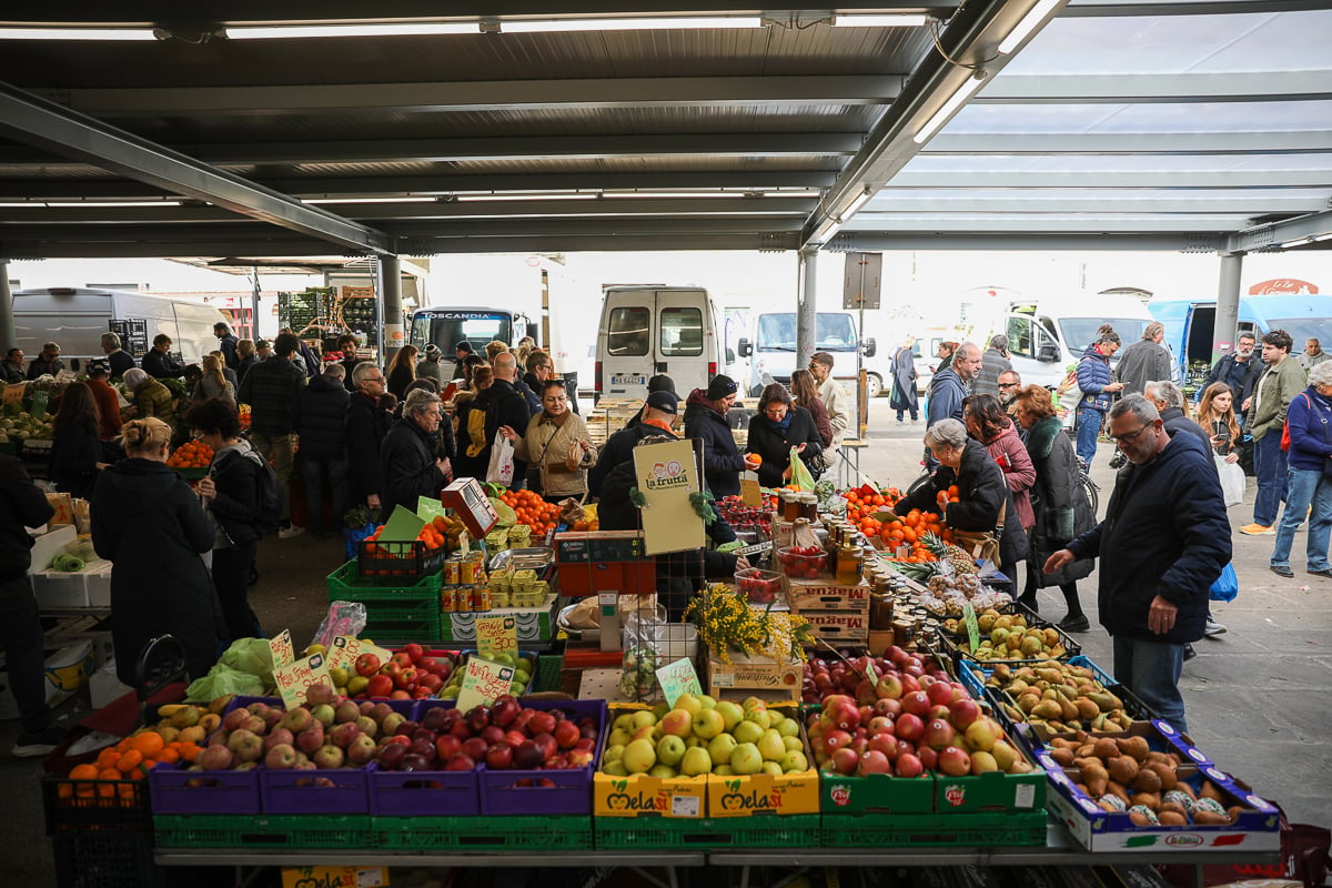 Outdoor produce stalls piled with fresh fruit at Mercato di Sant'Ambrogio, a local market in Florence.