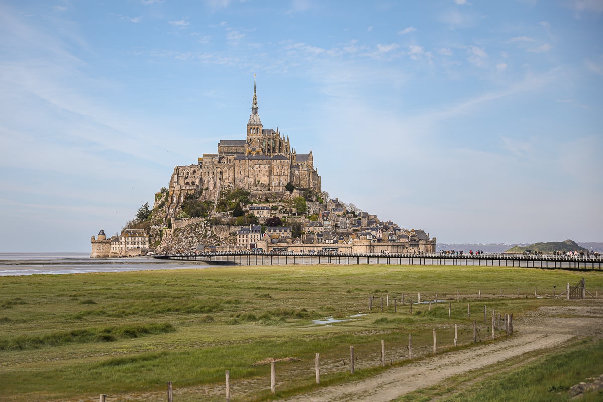 Mont Saint-Michel rising above the tidal bay and salt marshes, viewed from the causeway footpath, Normandy, France