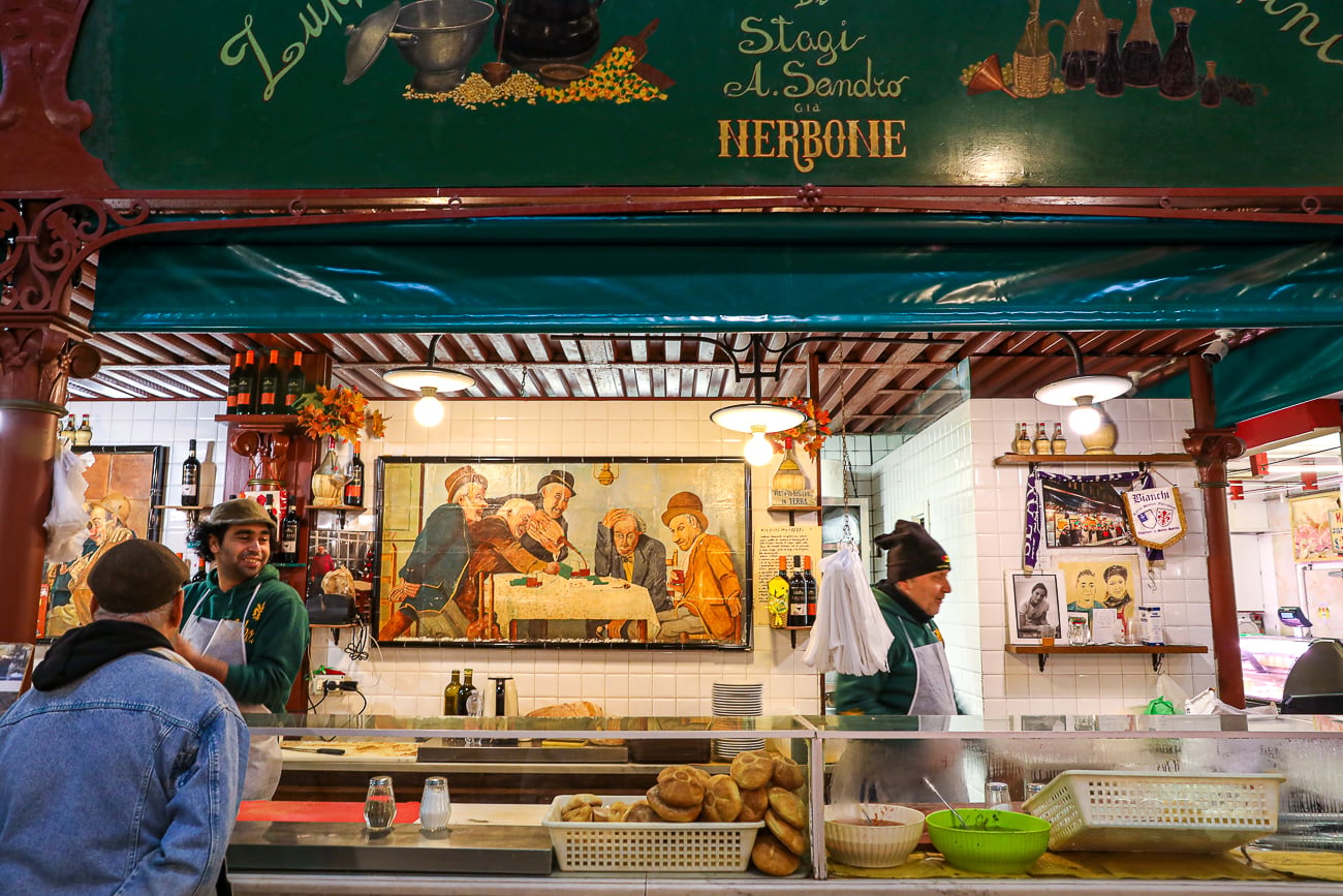 Historic green and red signage above the Nerbone food stall inside Mercato Centrale in Florence.