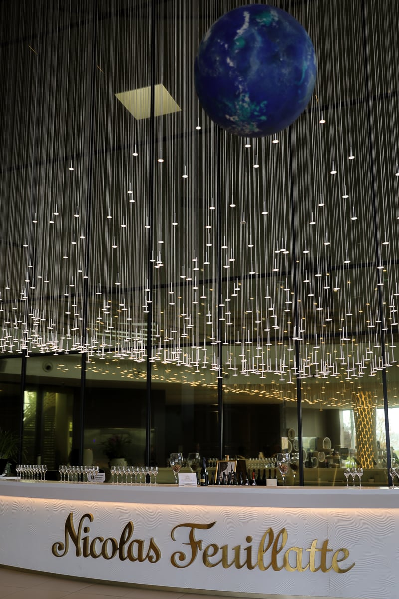 Tasting bar beneath a suspended globe and light installation at the Nicolas Feuillatte Champagne house