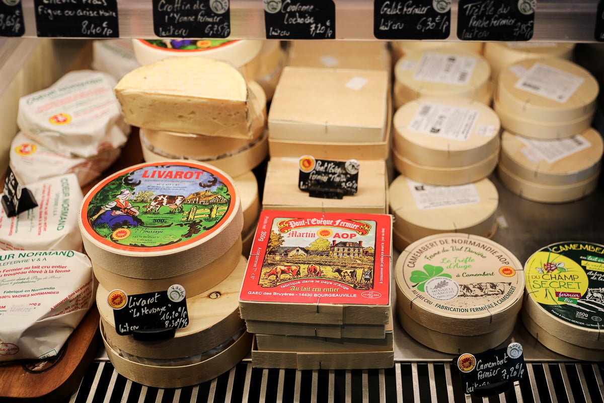 Wheels and boxes of Norman cheeses including Livarot, Pont-l'Évêque, and Camembert on display at a fromagerie in Bayeux