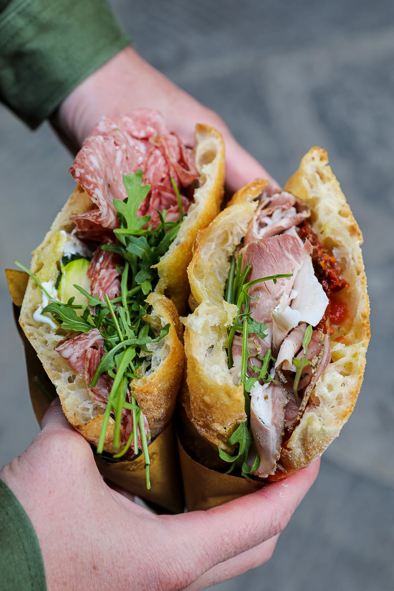 Two schiacciata sandwiches filled with salame, prosciutto, arugula, and sun-dried tomatoes from I' Girone De' Ghiotti in Florence.