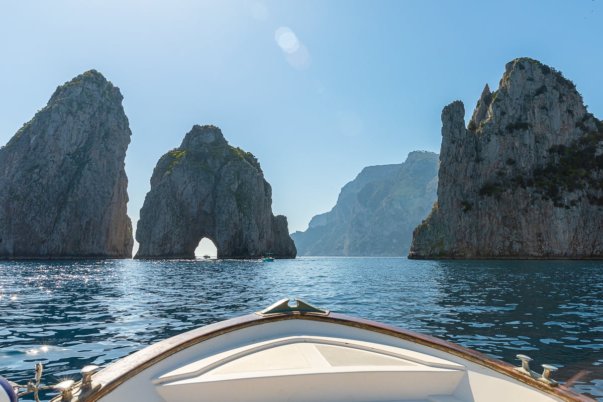 The Faraglioni sea stacks rising from turquoise water off the coast of Capri. A Capri boat tour is a must-do day trip from Naples.