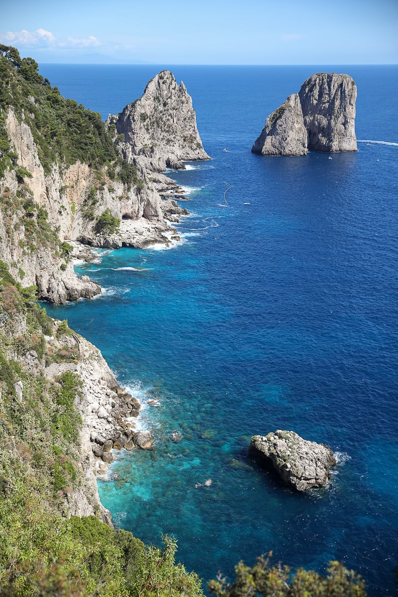 Tall limestone sea stacks (the Faraglioni) rising from deep blue water, a highlight of any day trip to Capri from Naples