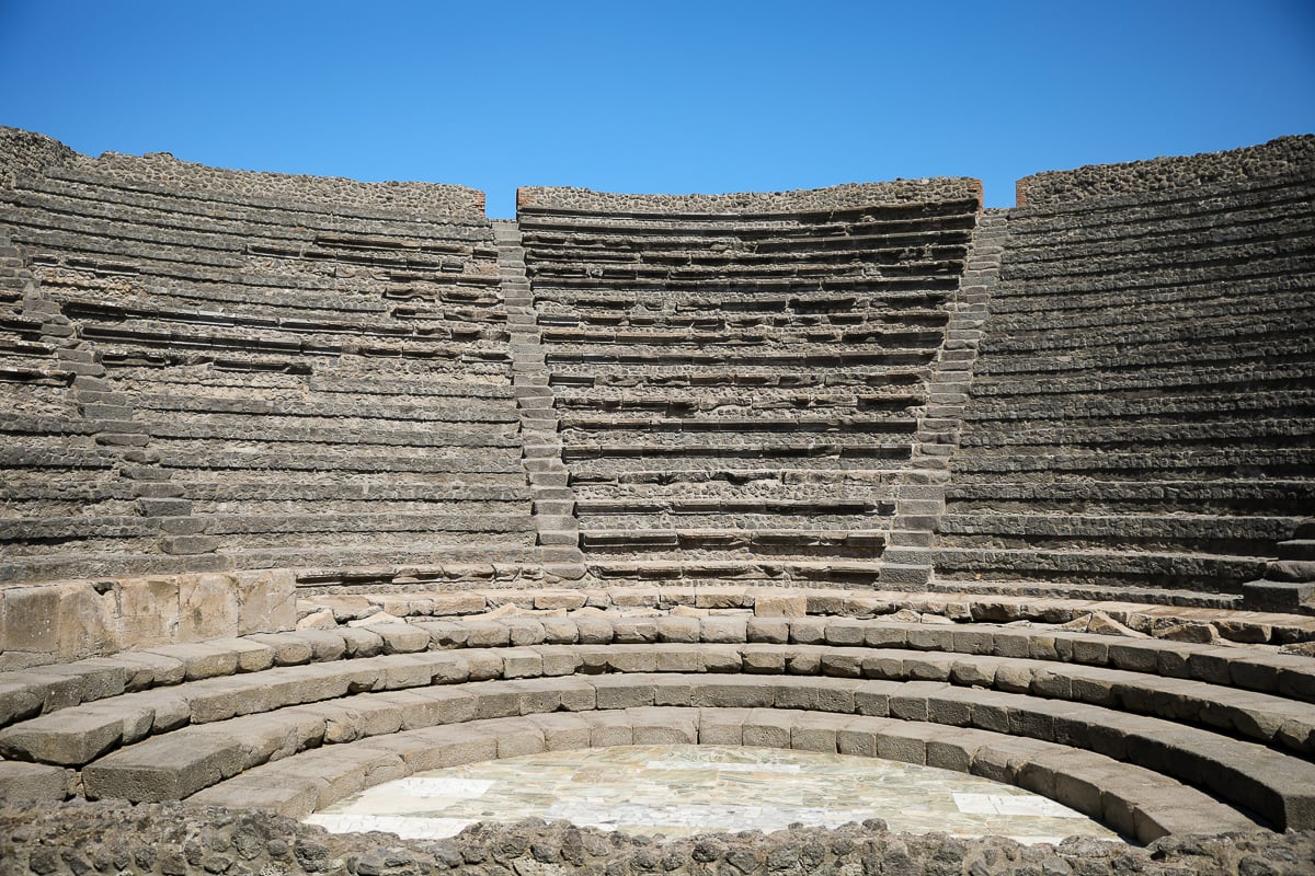An ancient stone theater in Pompeii under clear blue sky