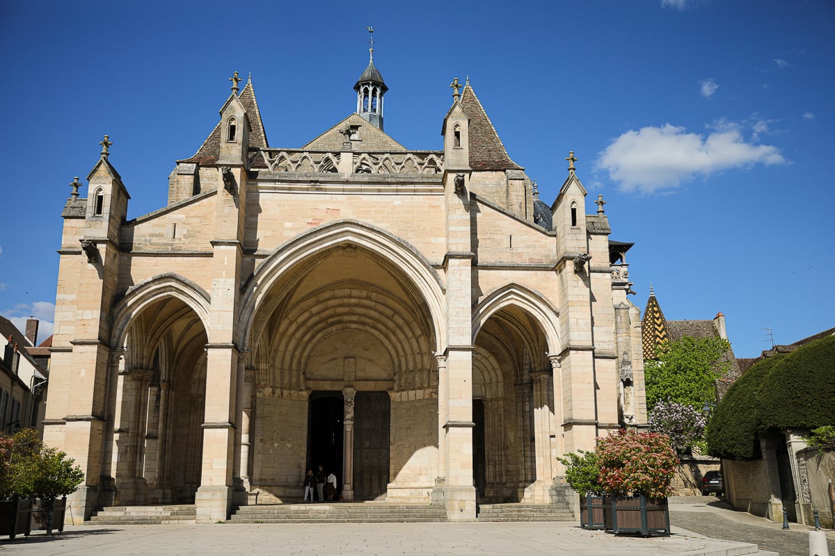 Romanesque and Gothic façade of the Basilique Notre-Dame de Beaune under a blue sky in Burgundy, France