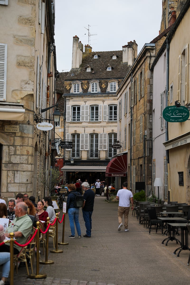 Historic pedestrian street lined with restaurants, cafés, and stone buildings in France