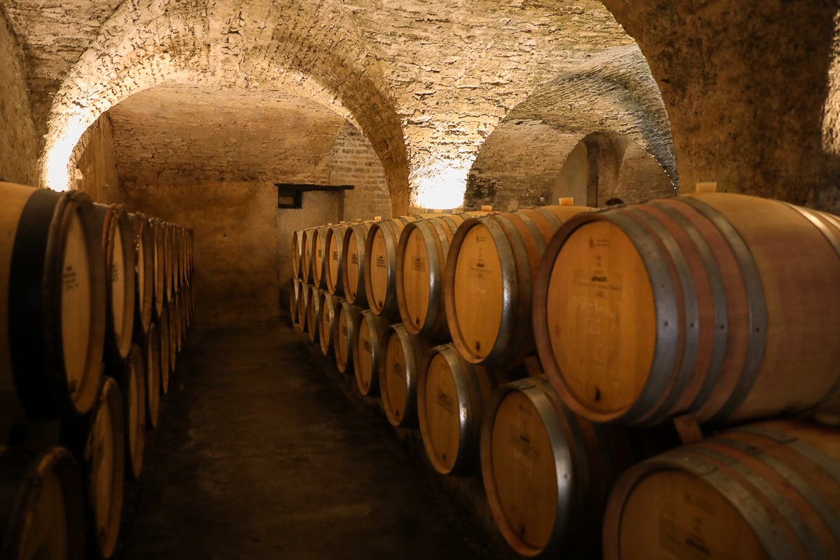 Rows of oak wine barrels inside a vaulted stone cellar in Burgundy, France