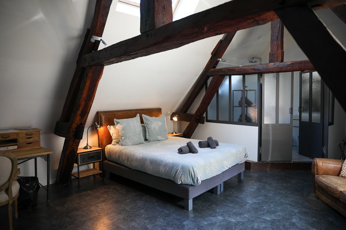 Loft-style suite with exposed wooden beams at La Maison de Maurice hotel in Beaune, France