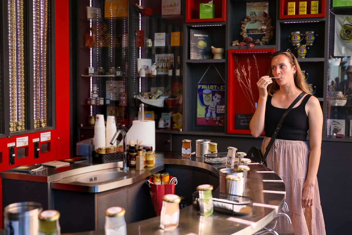 Woman sampling mustard at La Moutarderie Edmond Fallot tasting bar - one of the best things to do in Beaune, France