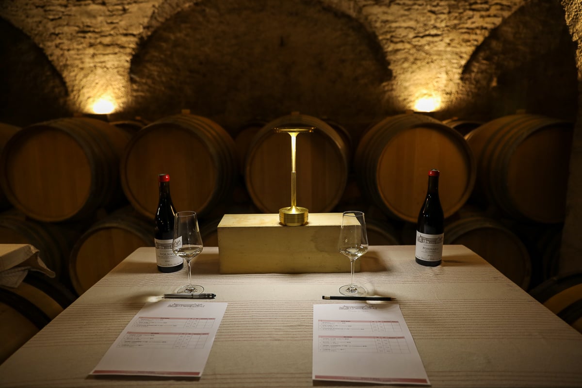 Burgundy wine tasting setup inside a vaulted stone cellar with oak barrels in the Côte d’Or