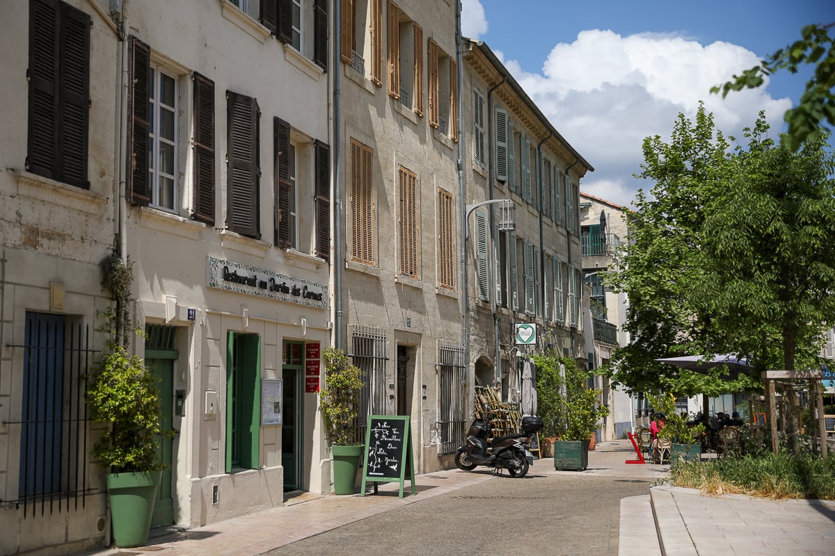 Historic street lined with cafés and stone buildings in Avignon, France