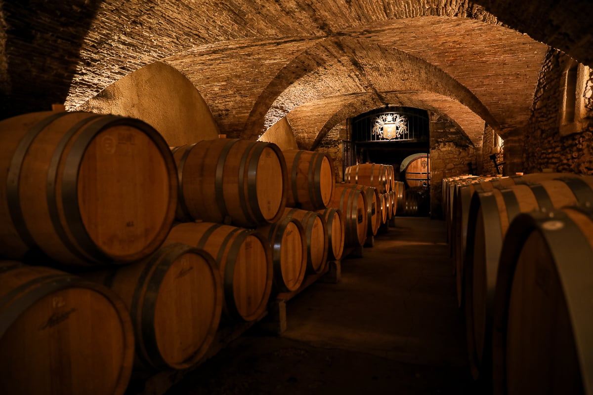 Oak wine barrels inside the historic cellar at Château La Nerthe in Châteauneuf-du-Pape