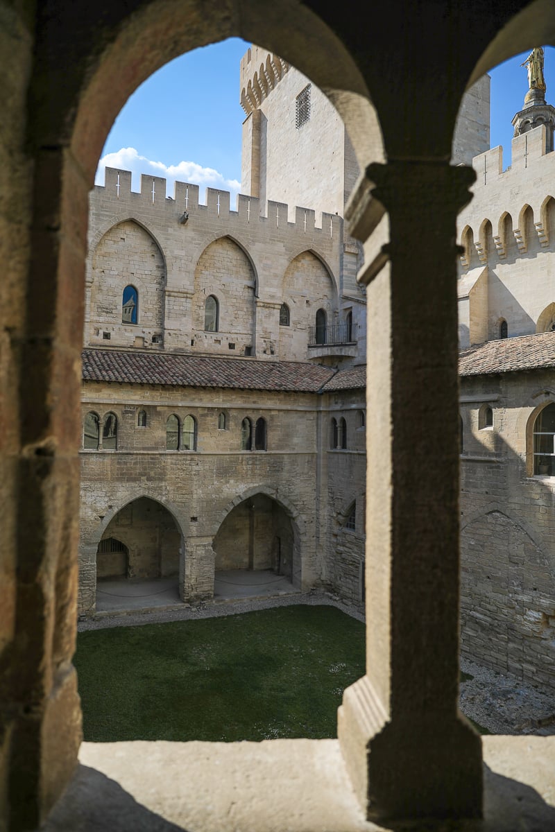 Stone courtyard inside the Palais des Papes in Avignon viewed through Gothic arches