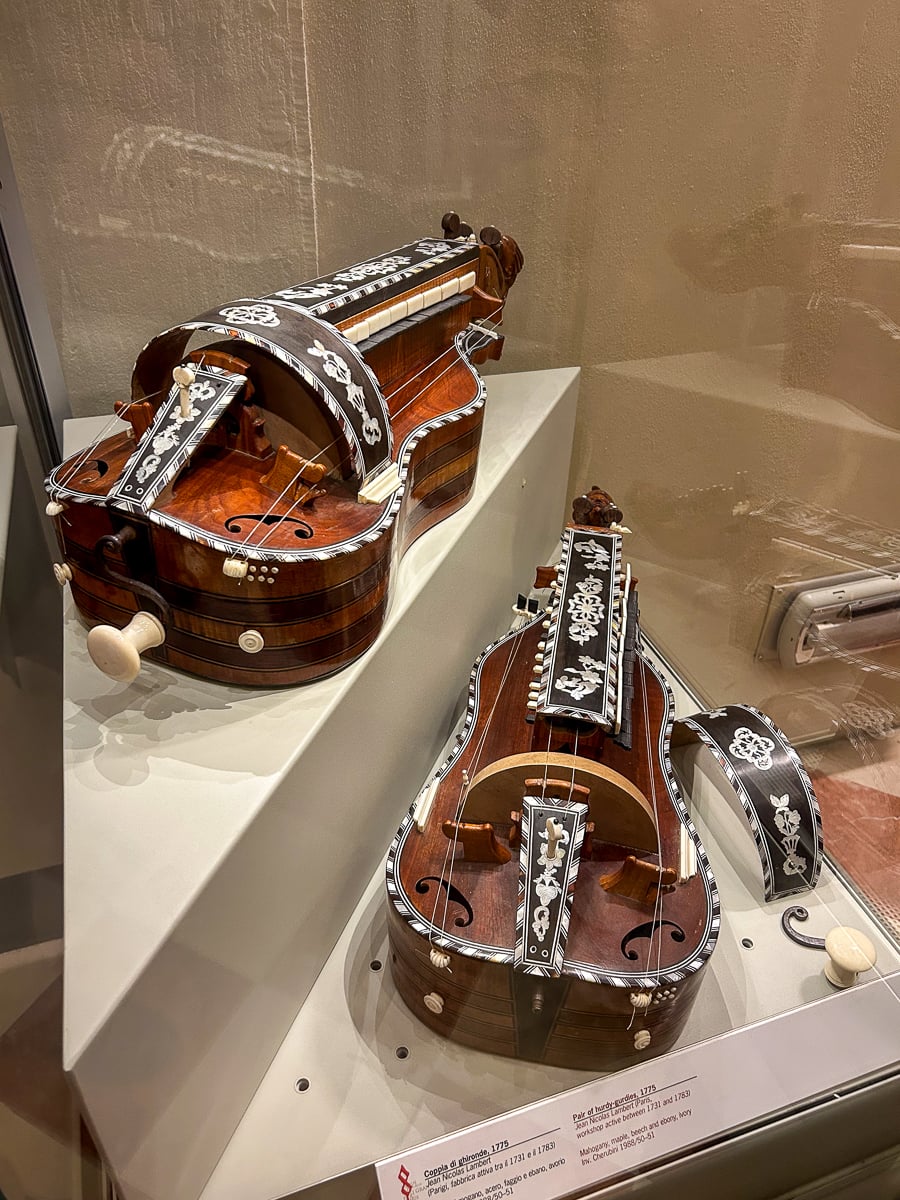 Ornately decorated historic string instruments on display inside Florence’s Accademia Gallery.