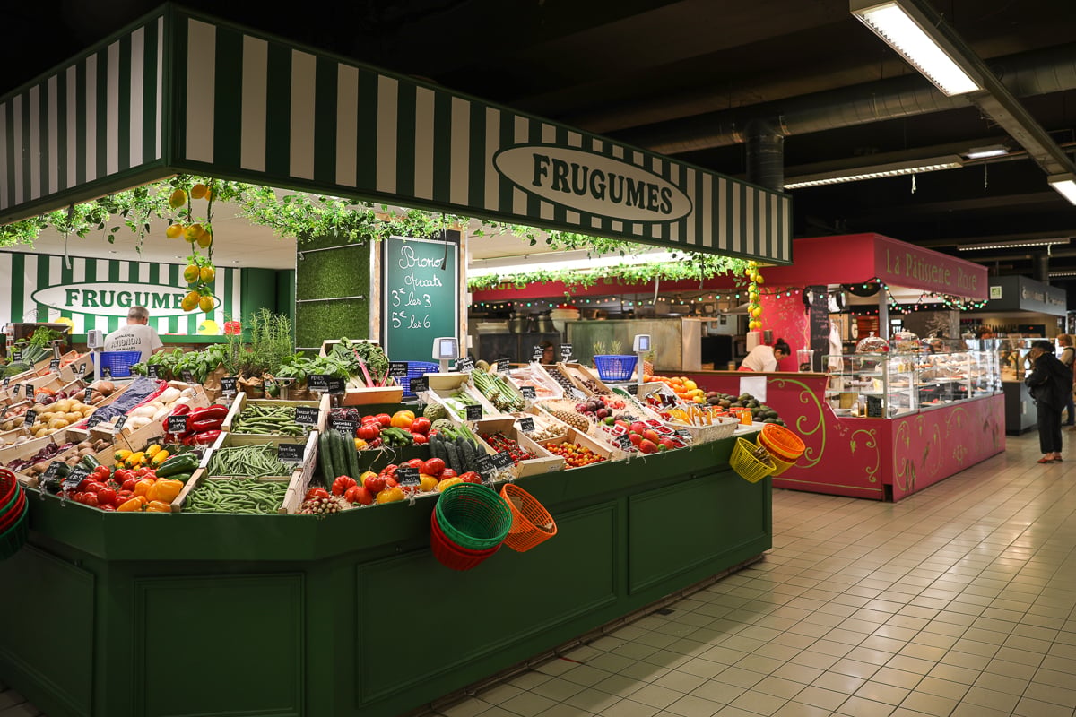 Fresh produce and pastry stalls inside Les Halles d’Avignon covered market