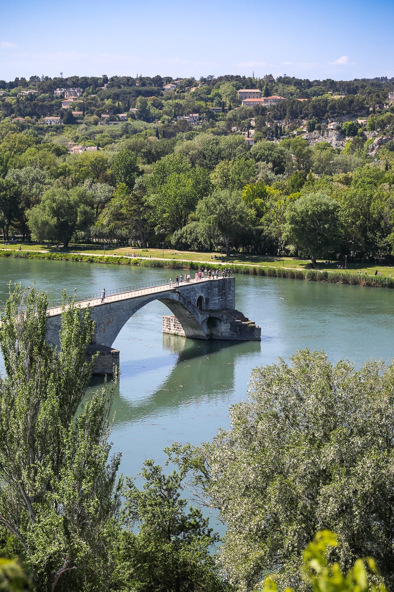Pont d’Avignon extending into the Rhône River beneath the green hills of Provence